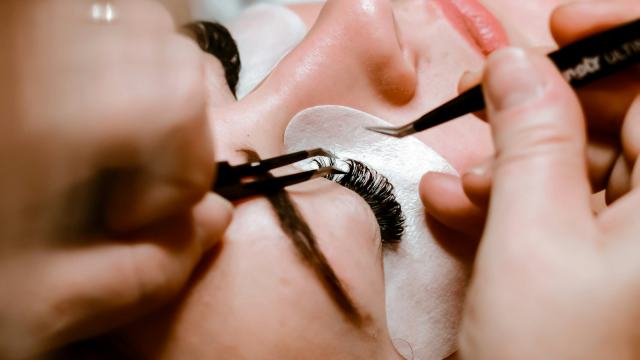 Lash designer aplicando extensão de cílios fio a fio com pinças