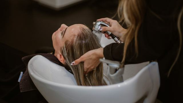 Cabeleireira lavando o cabelo de uma cliente no lavatório do salão