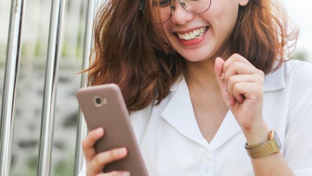 Mulher sorrindo ao ler uma mensagem no celular