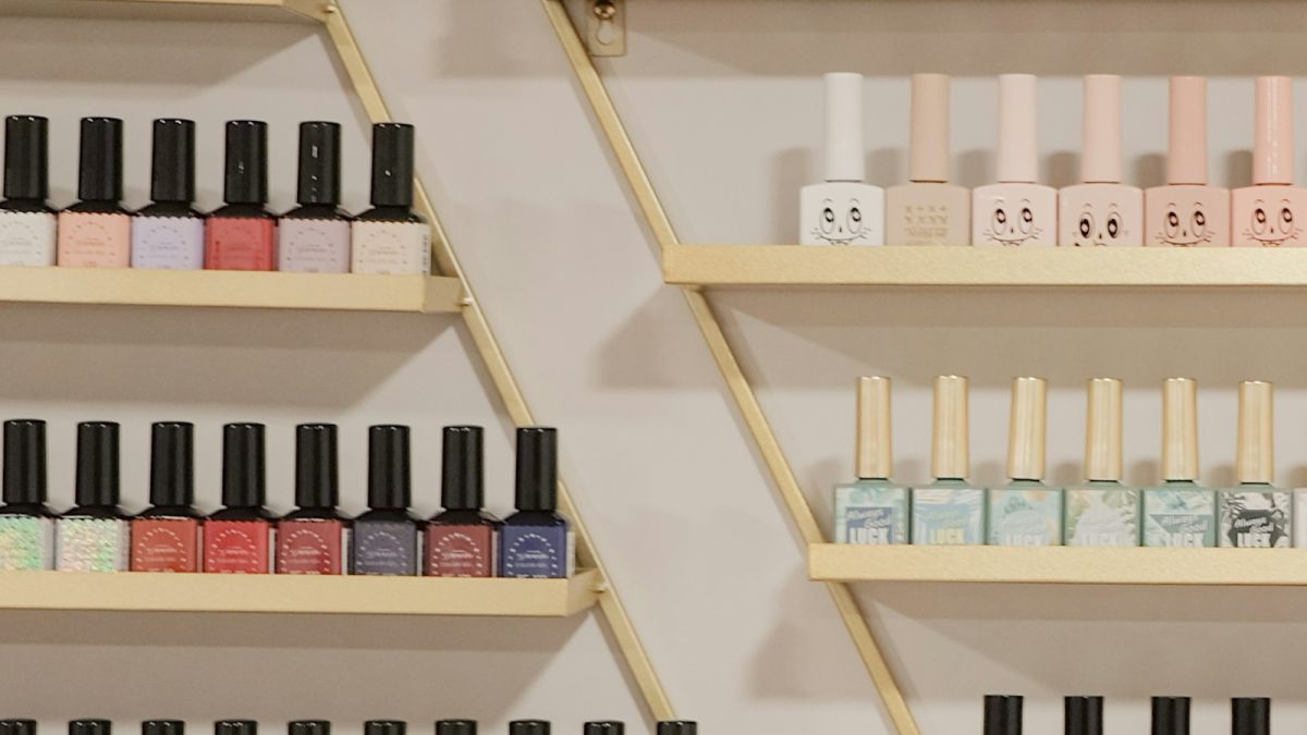 Prateleiras douradas com vidros de esmalte de várias cores organizados