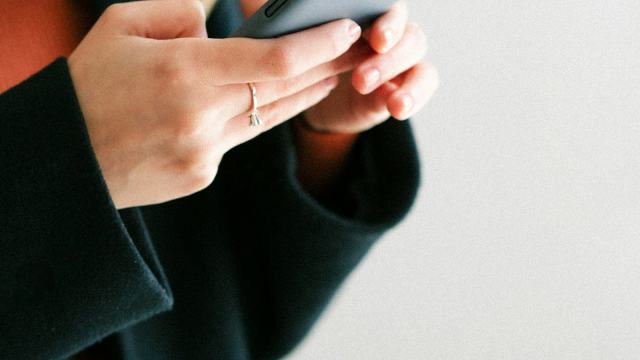 Mãos de mulher com unhas feitas segurando um celular